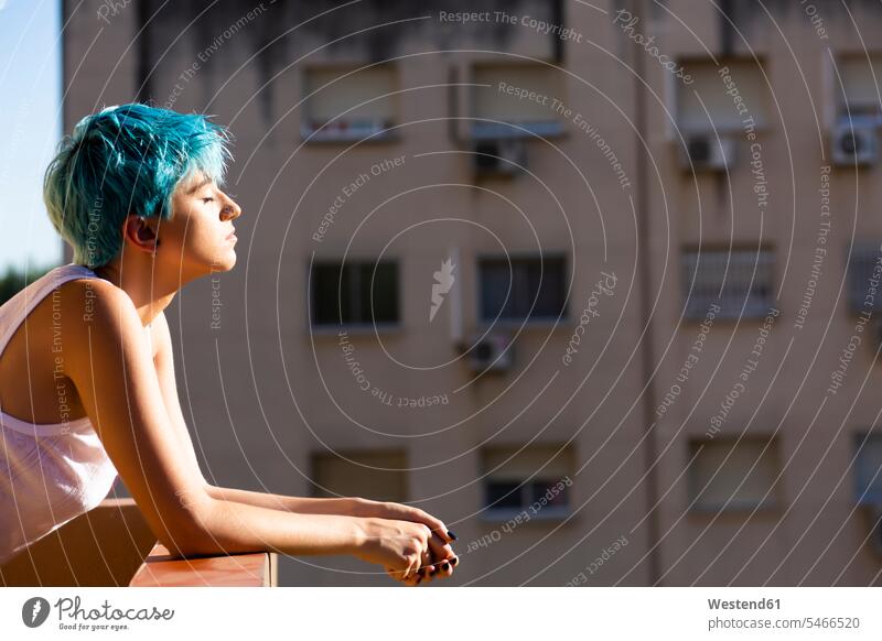Androgyne young woman with blue hair enjoying sunlight on balcony human human being human beings humans person persons caucasian appearance caucasian ethnicity