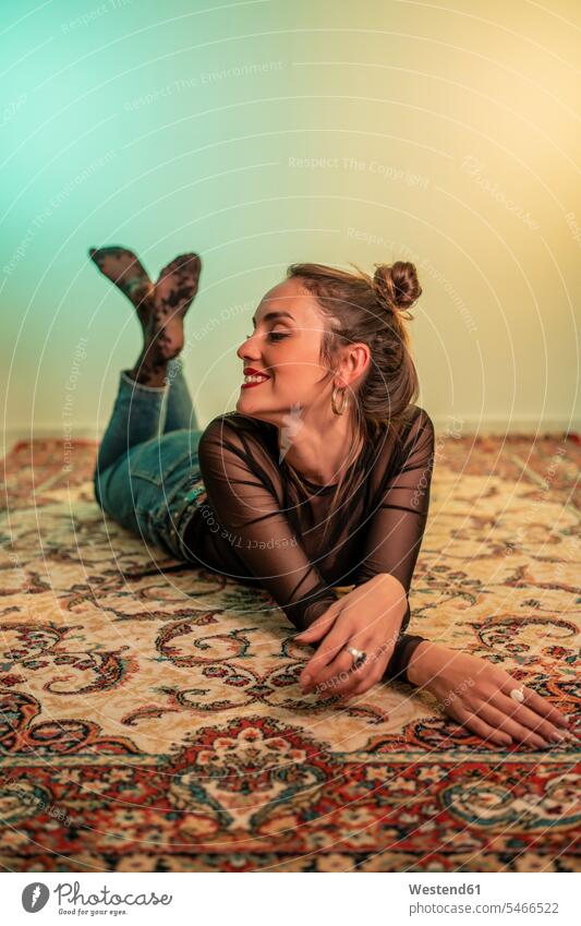 Portrait of smiling young woman lying on carpet carpets rug rugs smile delight enjoyment Pleasant pleasure happy Lifestyle Attractiveness beautiful good-looking