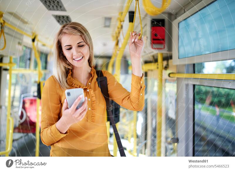 Smiling young woman using smartphone in a tram human human being human beings humans person persons caucasian appearance caucasian ethnicity european 1