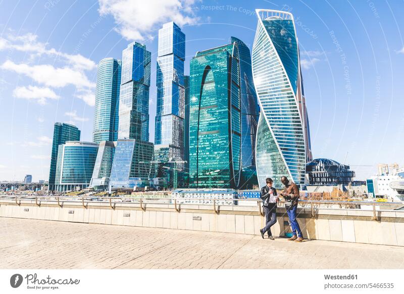 Russia, Moscow, two businessmen standing in front of modern office towers Businessman Business man Businessmen Business men business people businesspeople