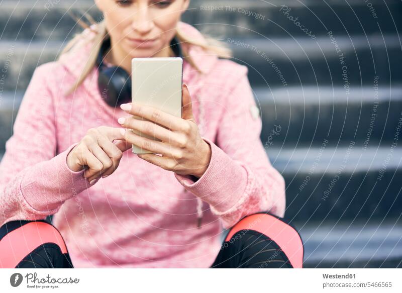 Sporty woman sitting on stairs, using smartphone human human being human beings humans person persons caucasian appearance caucasian ethnicity european 1