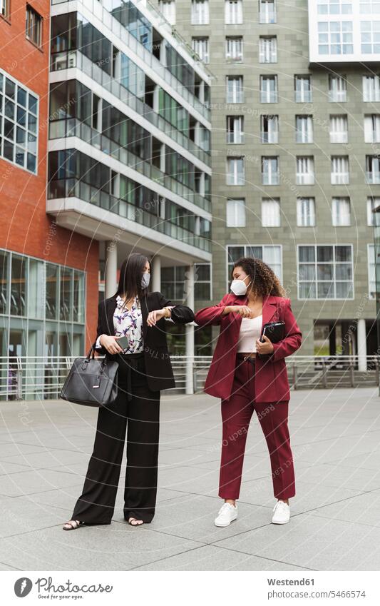 Young multi-ethnic female entrepreneur giving elbow bump against building in city color image colour image Spain outdoors location shots outdoor shot