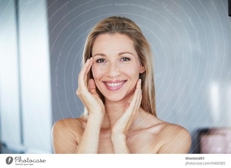 Portrait of smiling blond woman touching her face smile females women blond hair blonde hair faces portrait portraits Adults grown-ups grownups adult people