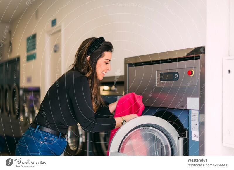 Young woman doing the laundry in a launderette human human being human beings humans person persons caucasian appearance caucasian ethnicity european 1