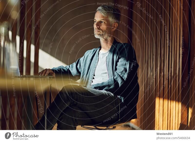 Casual businessman sitting in his sustainable office, thinking human human being human beings humans person persons caucasian appearance caucasian ethnicity