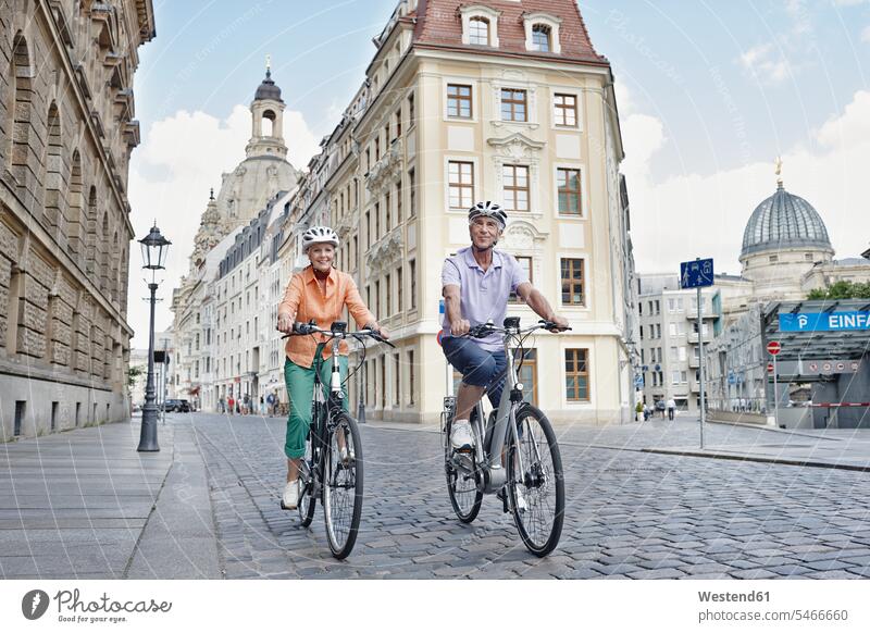 Senior tourists riding electric bicycle against Frauenkirche Cathedral at Dresden, Germany color image colour image outdoors location shots outdoor shot