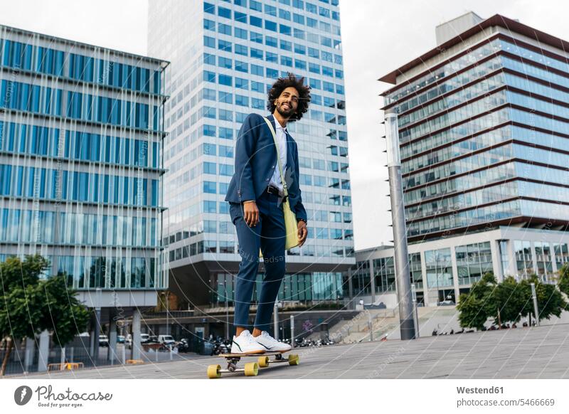 Spain, Barcelona, young businessman riding skateboard in the city Skate Board skateboards men males town cities towns Businessman Business man Businessmen