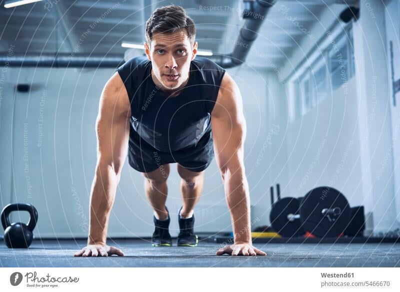 Athletic man doing pushups exercise at gym gyms Health Club men males workout working out work out Push-up Push-ups press-up press-ups Push Up Push Ups