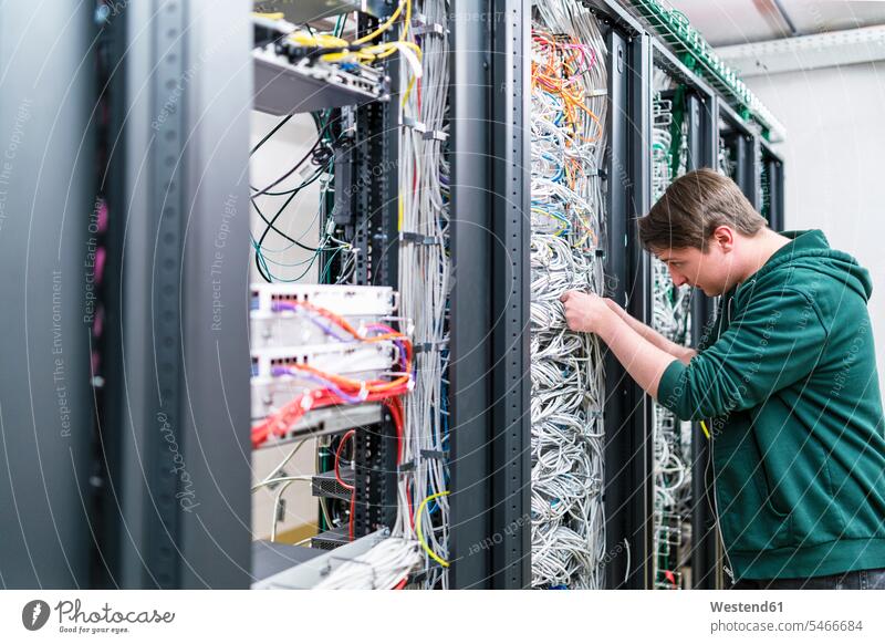 Teenager working with cables in server room At Work Teenage Boys male adolescent male adolescents male teenagers IT information technology Teens people persons