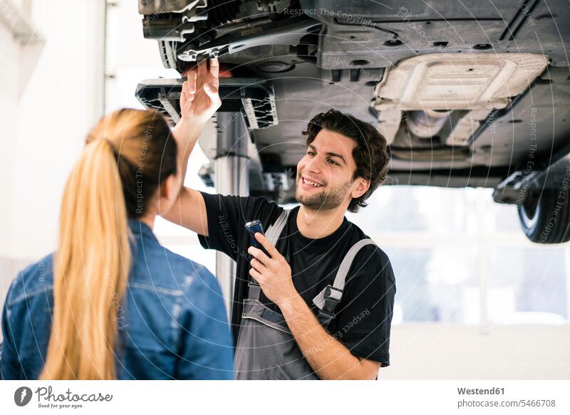 Car mechanic talking to client in workshop Occupation Work job jobs profession professional occupation industrial industries machinist machinists mechanician