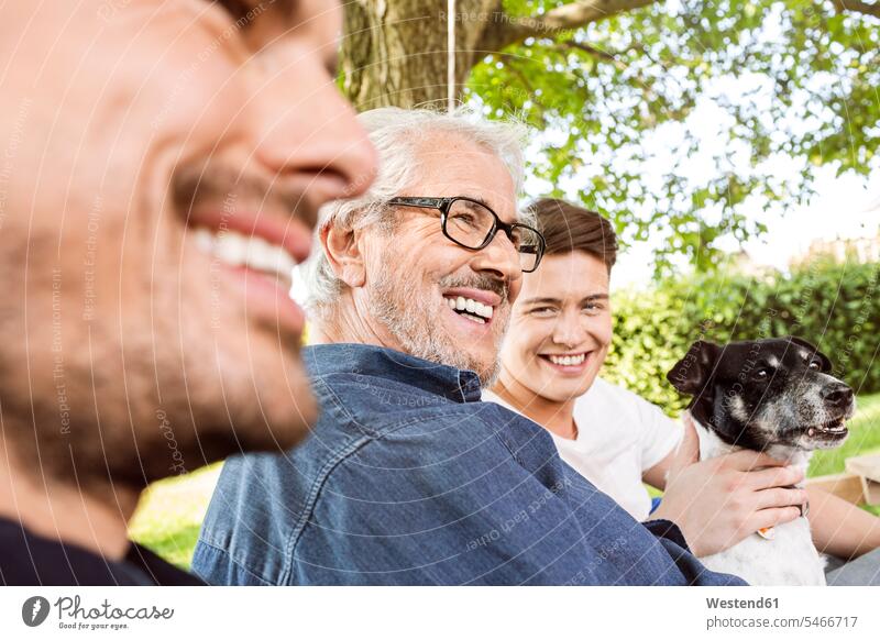 Men of a family sitting on a swing bed ing the garden, talking Germany mature men mature man young man young men only men quality of life Quality Time
