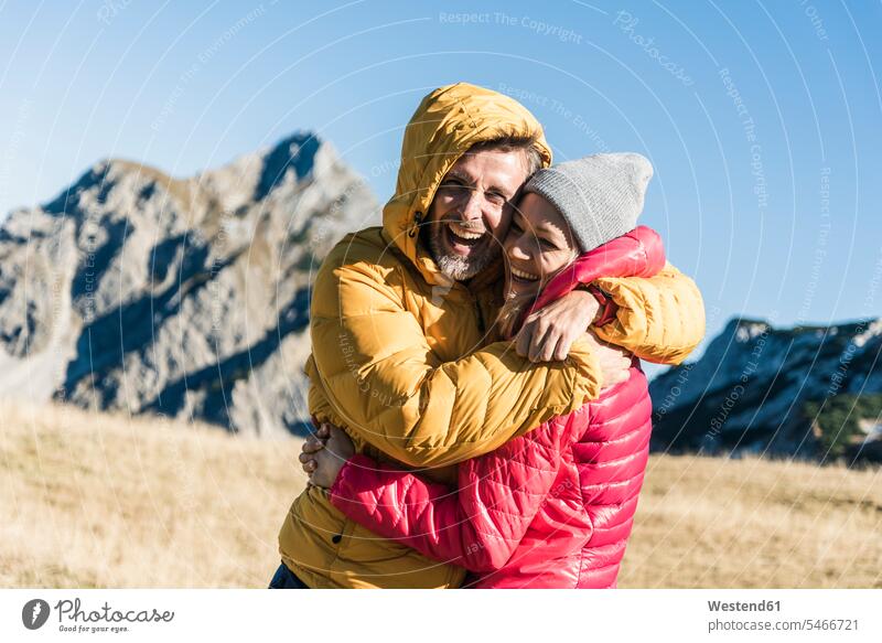 Austria, Tyrol, happy couple hugging on a hiking trip in the mountains happiness hiking tour walking tour mountain range mountain ranges embracing embrace