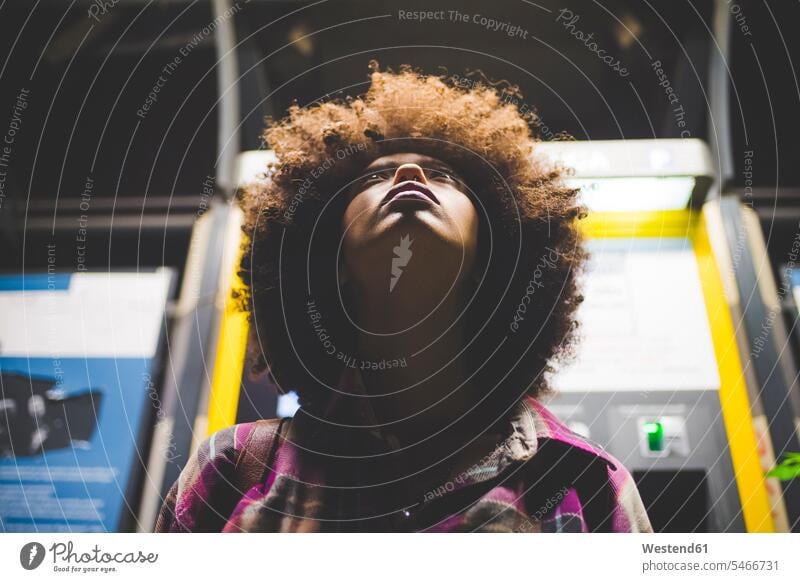 Young woman with afro hairdo at ticket machine at night looking up human human being human beings humans person persons curl curled curls curly hair jewelry