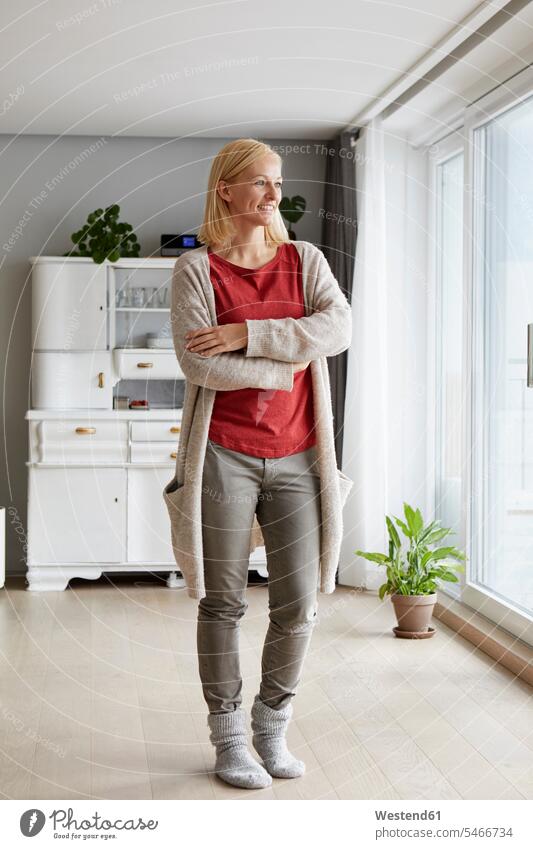 Confident woman standing in her comfortable home cozy sociable cosy thinking mature woman mature women confidence confident smiling smile at home females Adults