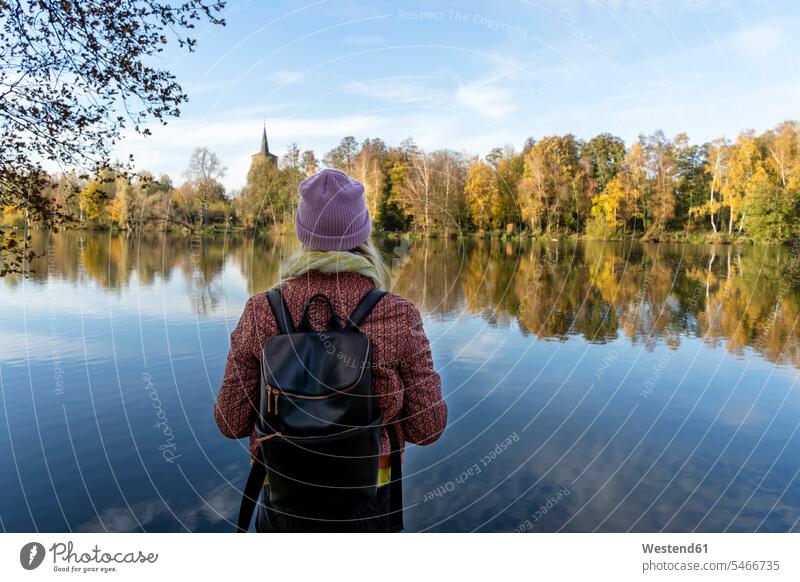Mid adult woman with backpack looking at lake against sky in forest color image colour image Germany outdoors location shots outdoor shot outdoor shots day