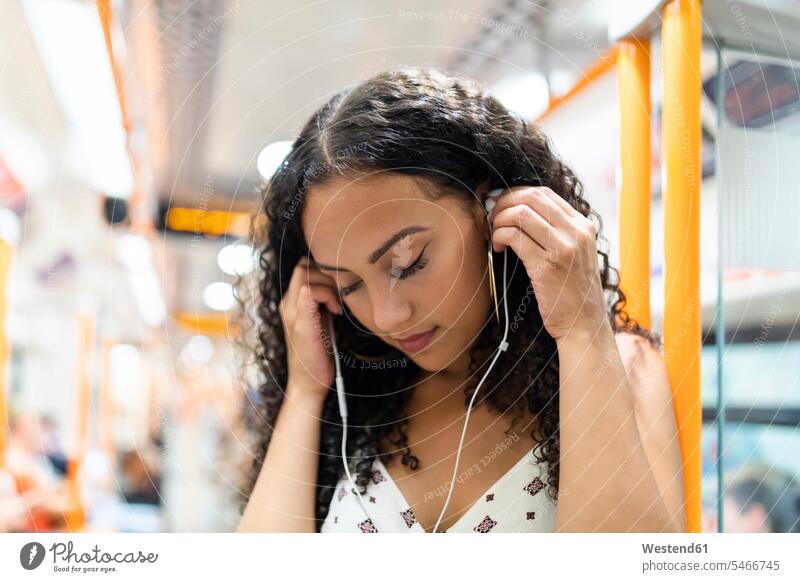 Young woman listening to music with earphones on the subway train earbuds Earbud In-Ear Headphones ear bud Ear buds in-ear females women beautiful