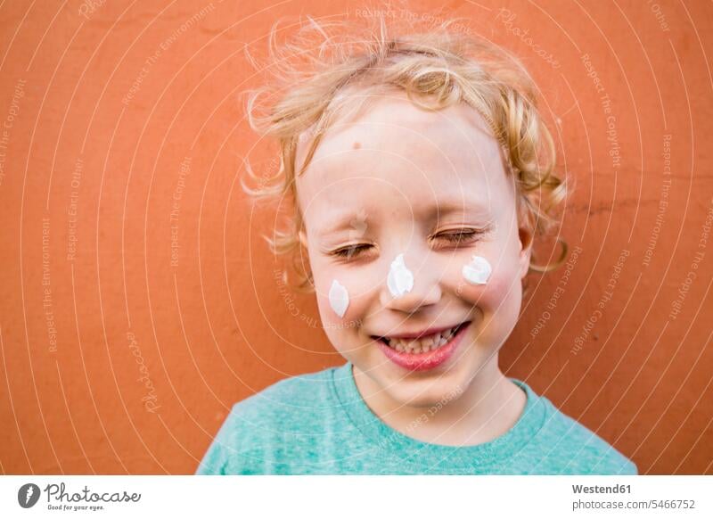 Portrait of smiling little boy with three blobs of cream on his face T- Shirt t-shirts tee-shirt cosmetic cream creams skin cream sun cream sun screen sunscreen