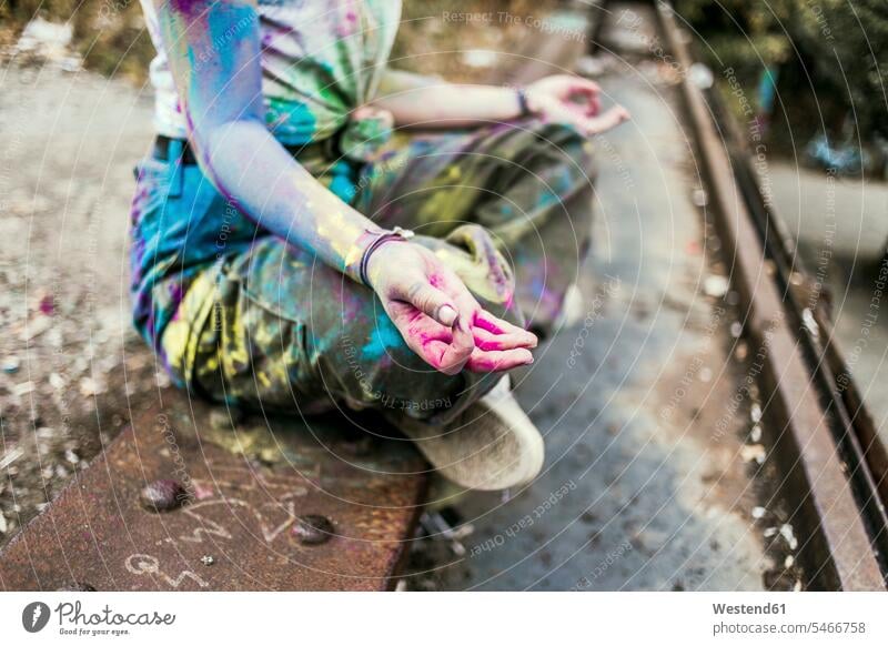 Girl with Holi colours on her clothes sitting on bridge, meditationg, Germany Seated Powder Paint mindfulness aware awareness self-care breaking ranks