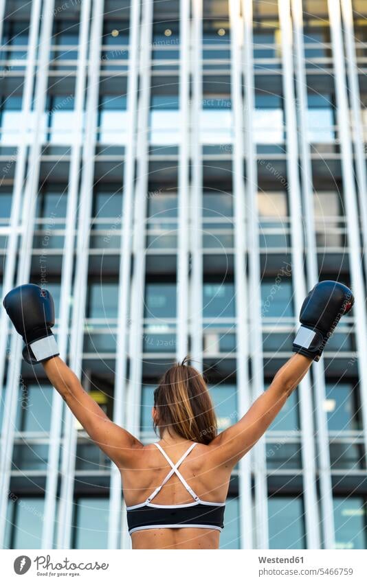 Sportive young woman with boxing gloves in the city raising her arms sportive sporting sporty athletic town cities towns females women sports martial arts
