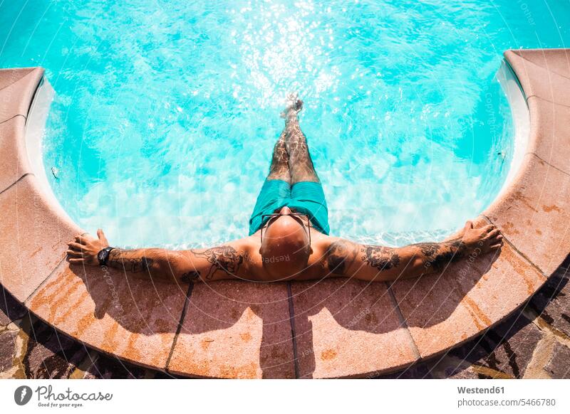 Man relaxing in swimming pool during sunny day color image colour image outdoors location shots outdoor shot outdoor shots daylight shot daylight shots