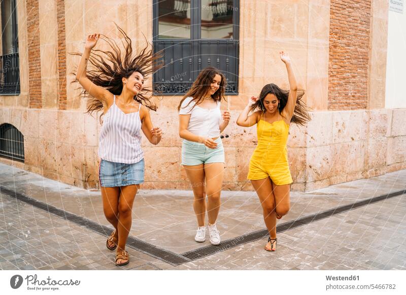 Three carefree female friends in the city mate dark-haired brown haired brunette go going walk smile seasons summer time summertime summery Ardor Ardour