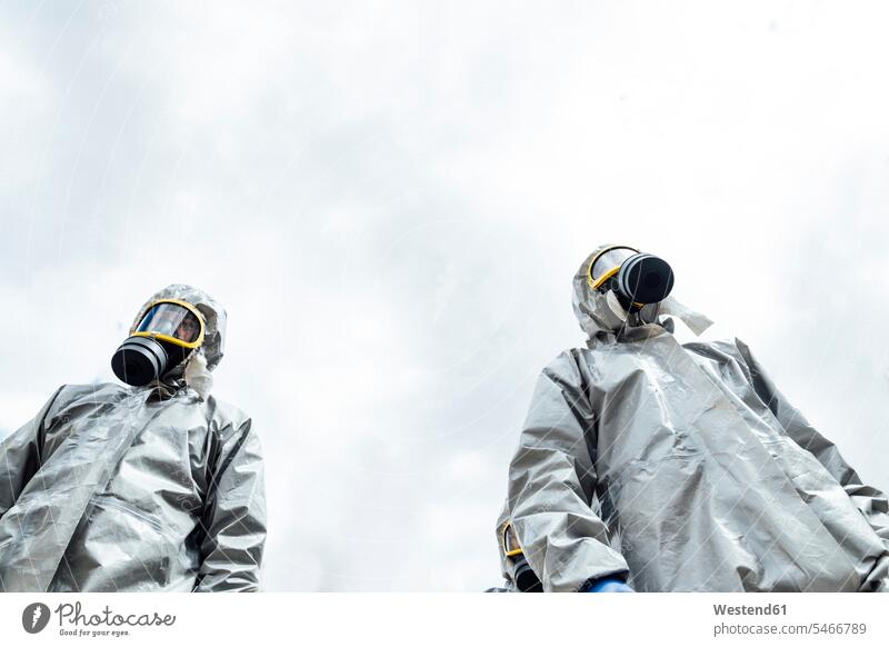 Low angle view of disinfection coworkers in protective coveralls in city against sky color image colour image Corona Virus Coronavirus disease Covid-19 COVID19