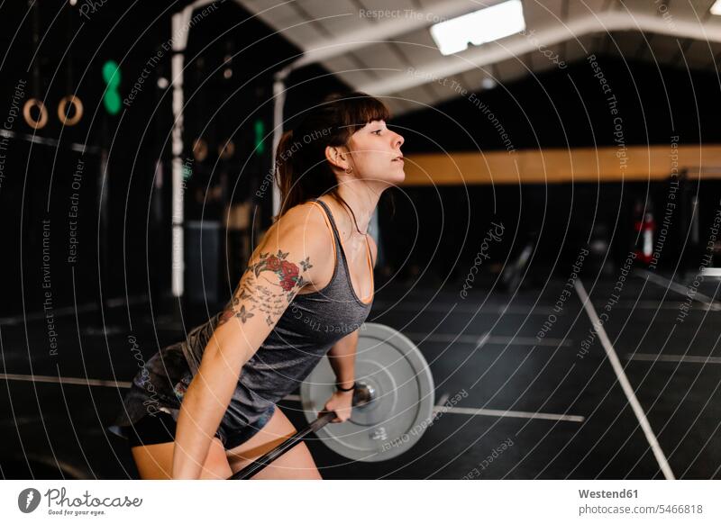 Mid adult woman lifting deadlift while standing in health club color image colour image Spain indoors indoor shot indoor shots interior interior view Interiors