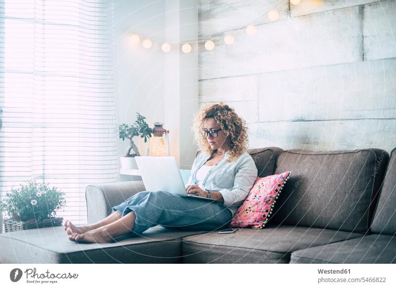Woman using laptop on couch at home freelancer freelancing Mobility mobile curly curly hair curls curled Connection connected Connections connectivity
