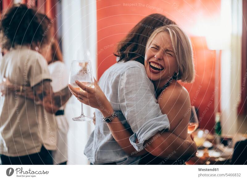 Happy young woman embracing male friend during party at home color image colour image indoors indoor shot indoor shots interior interior view Interiors