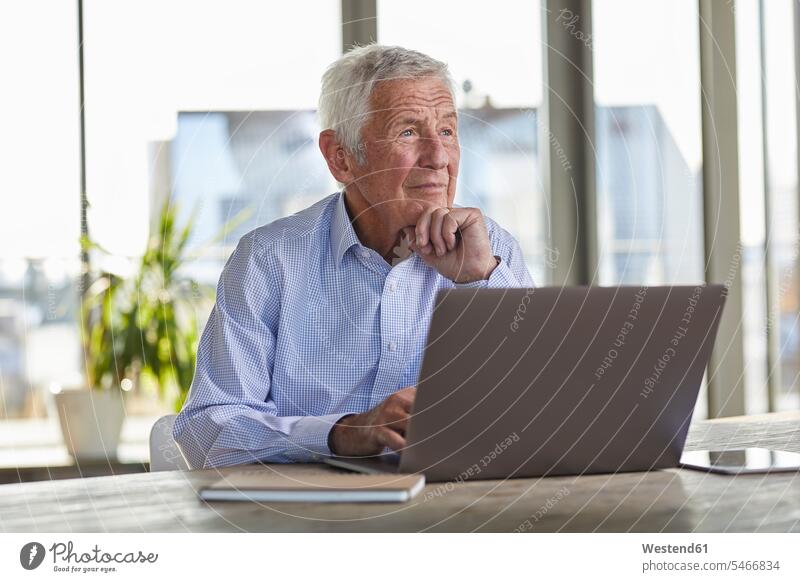 Portrait of pensive senior man sitting at table with laptop looking at distance senior men elder man elder men senior citizen thoughtful Reflective