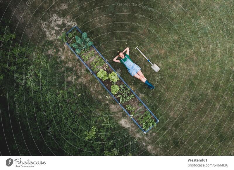 Drone shot of woman with hands behind head lying by raised bed on land color image colour image Austria casual clothing casual wear leisure wear casual clothes