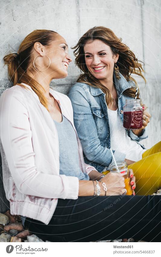 Two female friends drinking smoothies outdoors having fun Smoothies Fun funny mate friendship Drink beverages Drinks Beverage food and drink Nutrition