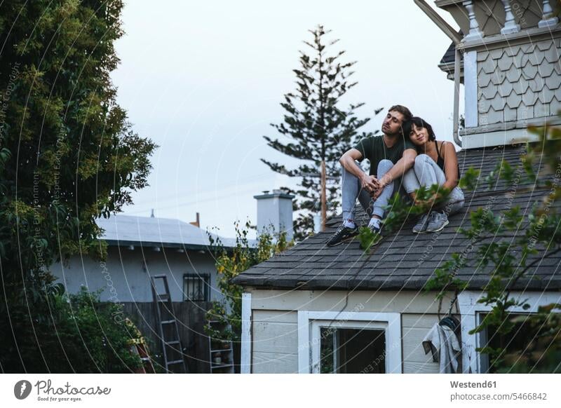 Relaxed couple sitting on roof relaxed relaxation Seated twosomes partnership couples Roof relaxing people persons human being humans human beings happiness