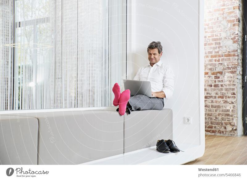 Businessman with pink socks using laptop in office Laptop Computers laptops notebook Business man Businessmen Business men offices office room office rooms