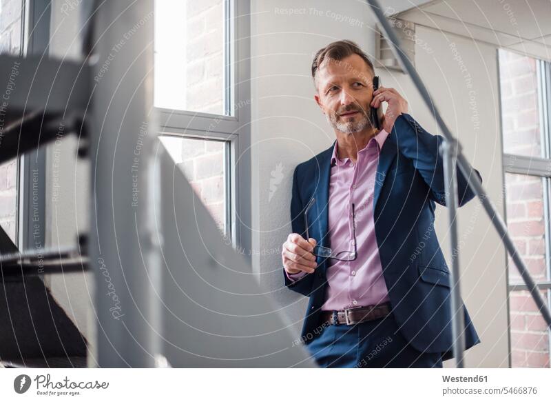 Mature businessman on cell phone at the window confidence confident on the phone call telephoning On The Telephone calling Businessman Business man Businessmen