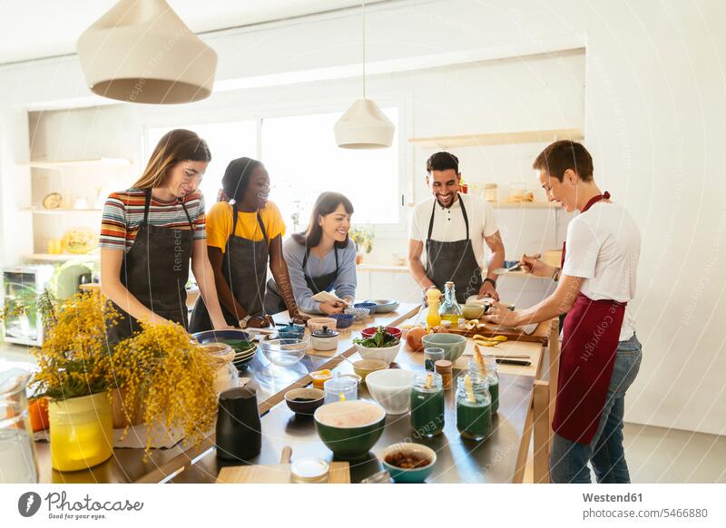 Friends and instructor in a cooking workshop preparing food female cook kitchen friends mate training course Exercise Class Training Class Food Preparation