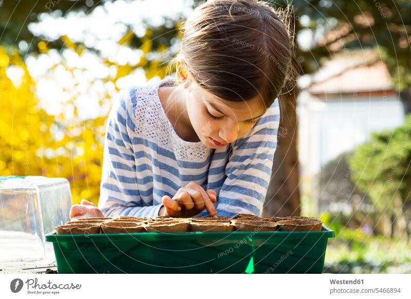 Girl looking at nursery pots with soil in her little greenhouse flower pot flower pots flowerpots Tables discover discovering stand horticulture yard work