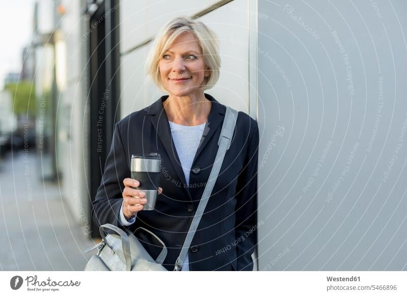 Smiling senior businesswoman with takeaway coffee outdoors businesswomen business woman business women confidence confident smiling smile business people