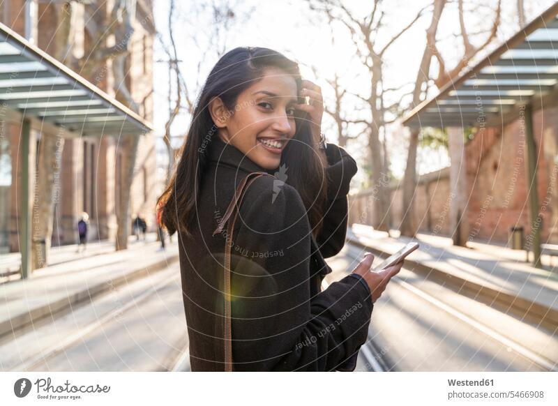 Portrait of happy young woman with smartphone on tram line transport railroad railroads Railways streetcar streetcars trams tramways telecommunication phones