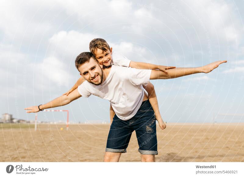 Man carrying boy piggyback on the beach T- Shirt t-shirts tee-shirt balls celebrate partying cheer exultation jubilate jubilating rejoice rejoicing smile play