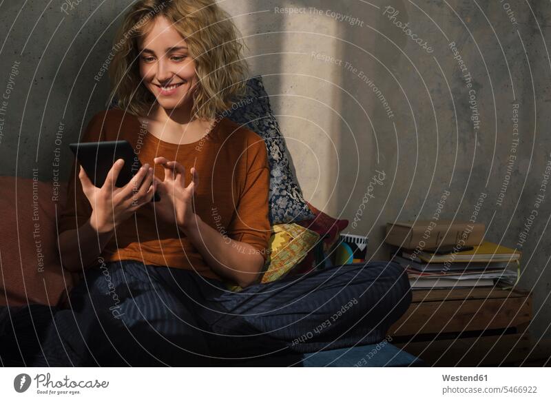 Portrait of smiling young woman sitting on bed using E-book reader human human being human beings humans person persons caucasian appearance caucasian ethnicity
