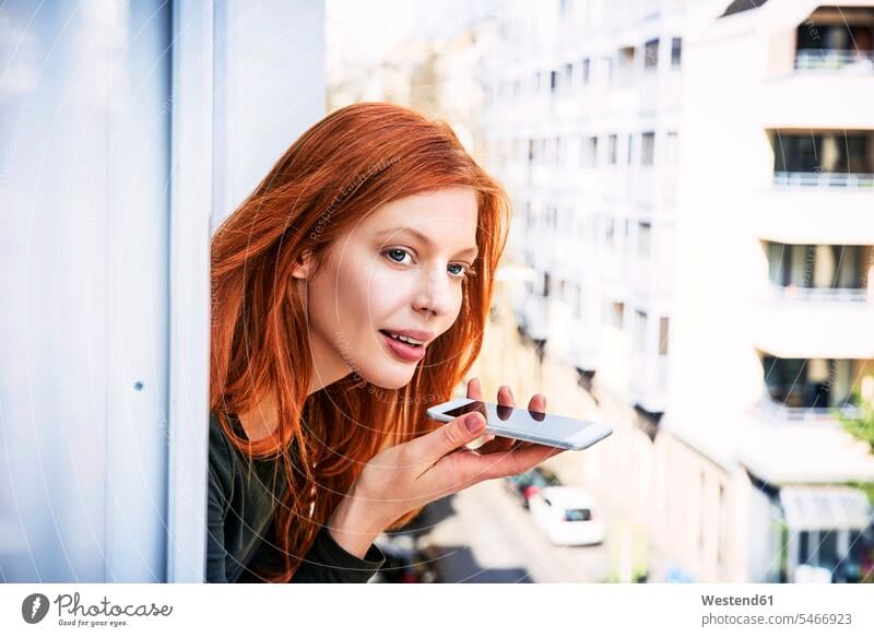 Portrait of redheaded woman on the phone leaning out of window females women windows portrait portraits red hair red hairs red-haired call telephoning
