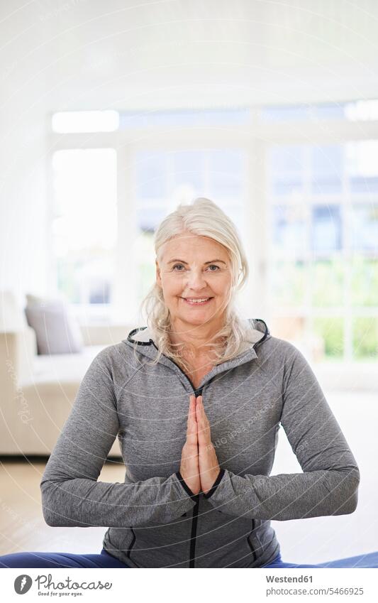 Smiling senior woman with hands clasped exercising at home color image colour image indoors indoor shot indoor shots interior interior view Interiors day