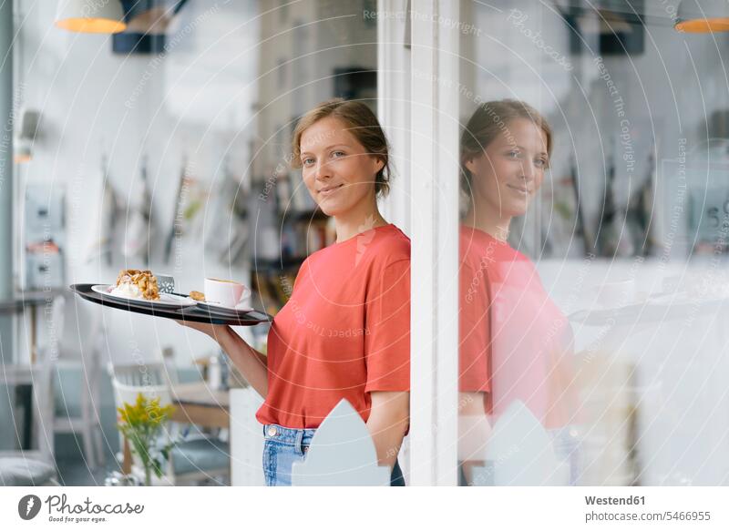 Portrait of smiling young woman serving coffee and cake in a cafe pies cakes portrait portraits Coffee serve females women Sweet Food sweet foods food and drink