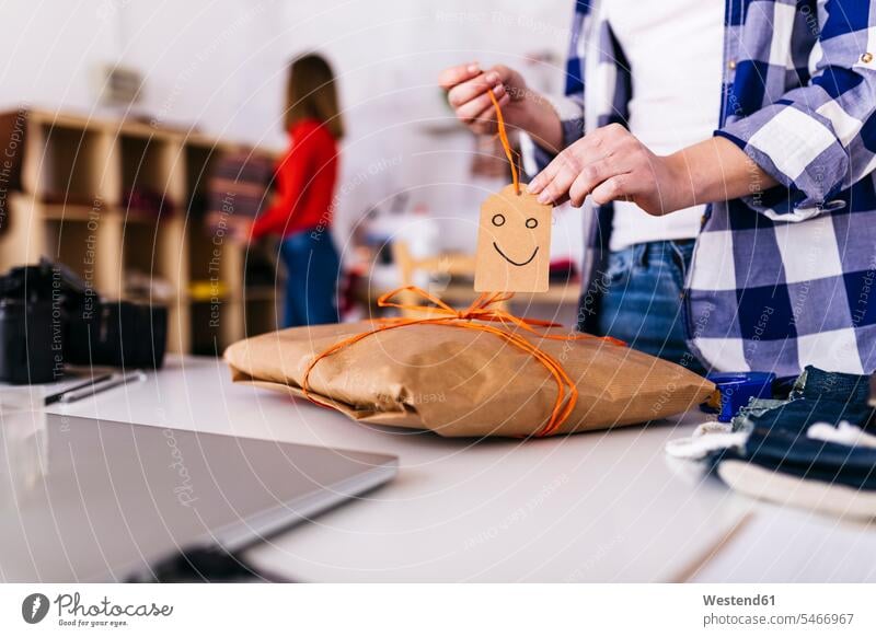 Close-up of fashion designer wrapping a package in studio with smiley face parcel packet packets parcels studios woman females women fashionable happy face