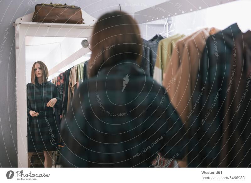 Young woman trying dress while looking in mirror at design studio color image colour image leisure activity leisure activities free time leisure time