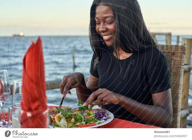 Young woman enjoying a dinner at the waterfront, Maputo, Mozambique human human being human beings humans person persons African black black ethnicity coloured