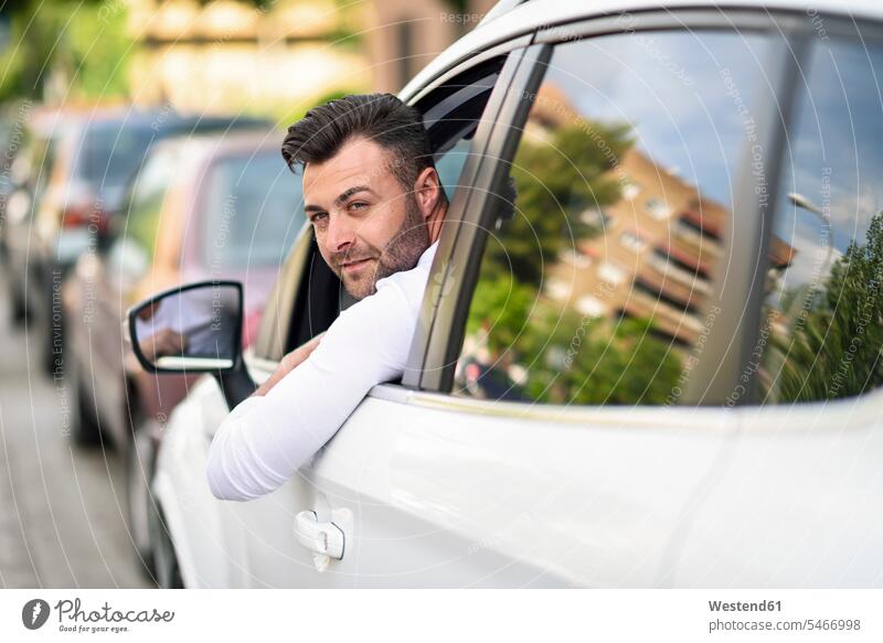 Man leaning out the window of his car in the city town cities towns man men males automobile Auto cars motorcars Automobiles outdoors outdoor shots