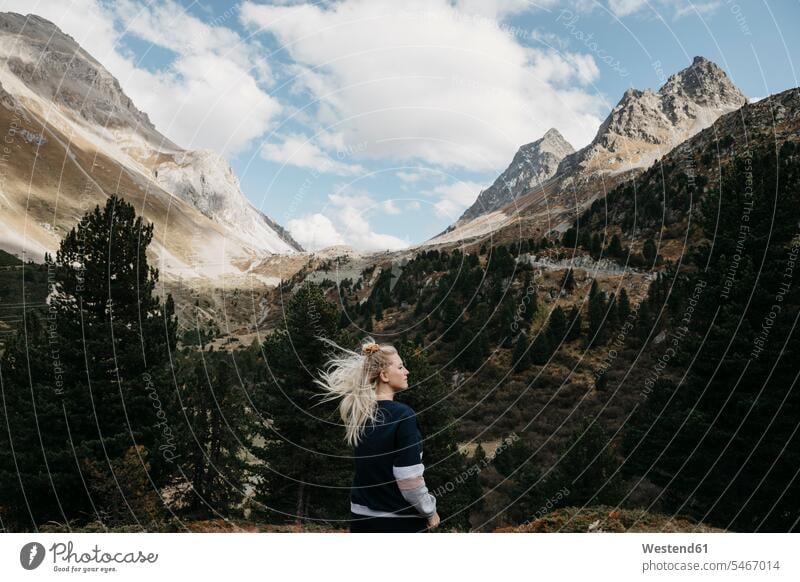 Switzerland, Grisons, Albula Pass, young woman with windswept hair standing in mountainscape females women Windswept Windblown Windy mountain range