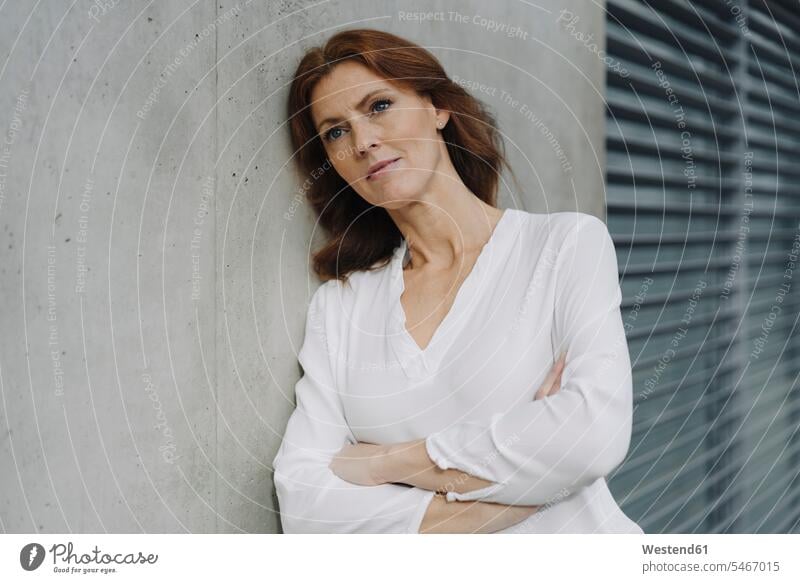Portait of a pensive businesswoman leaning against a concrete wall human human being human beings humans person persons caucasian appearance caucasian ethnicity